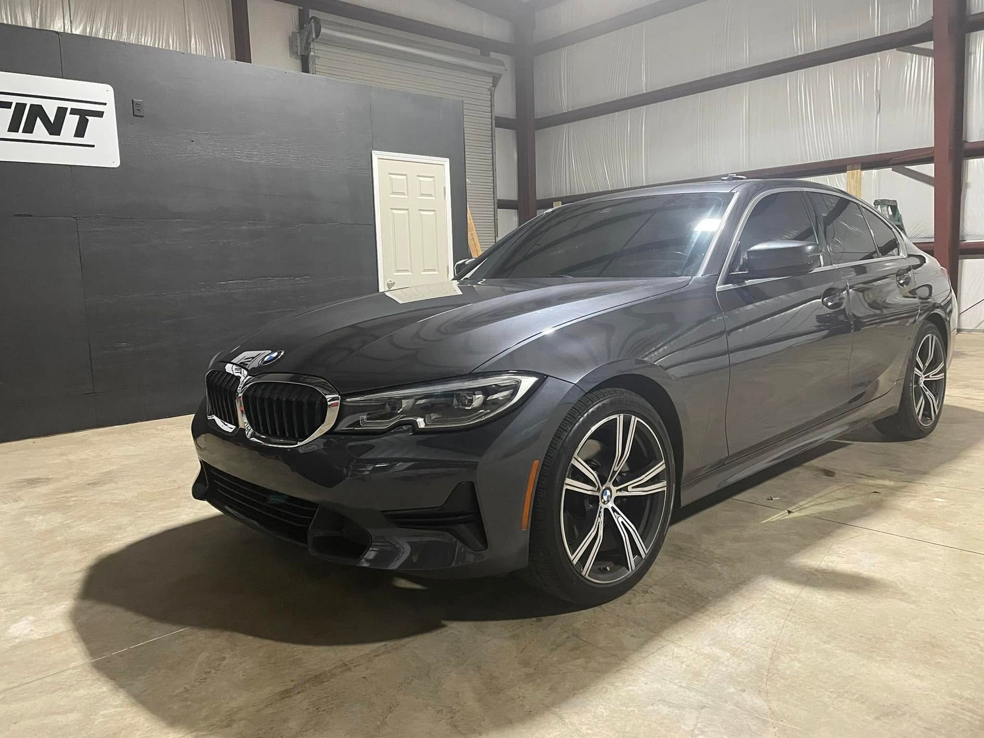 A gray bmw 3 series is parked in a garage.