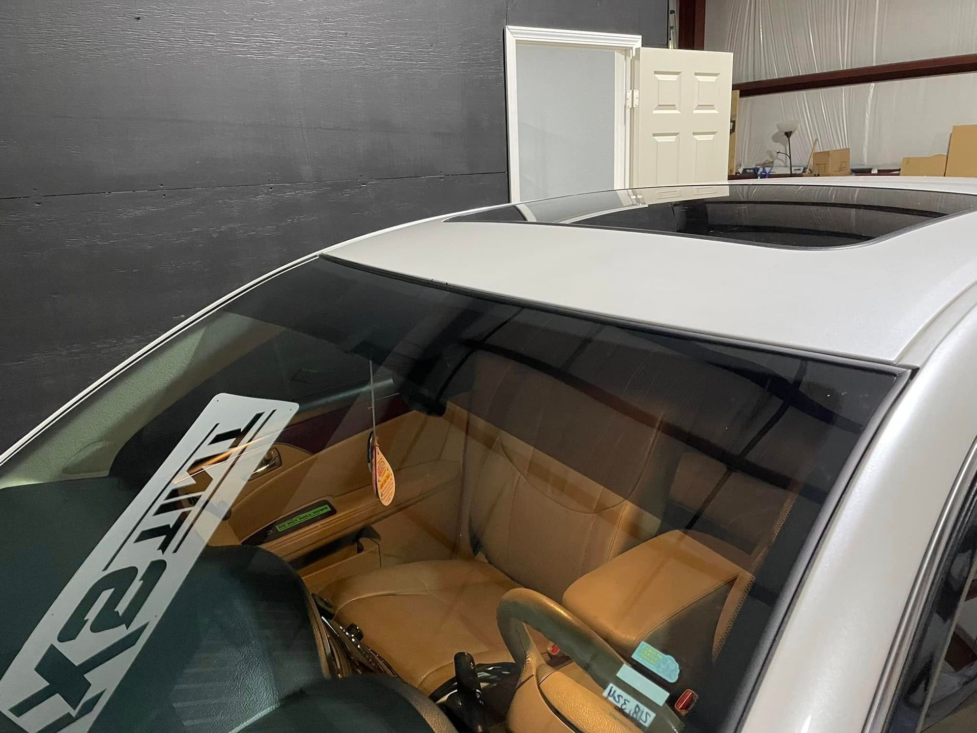 A white car with a sunroof is parked in a garage.