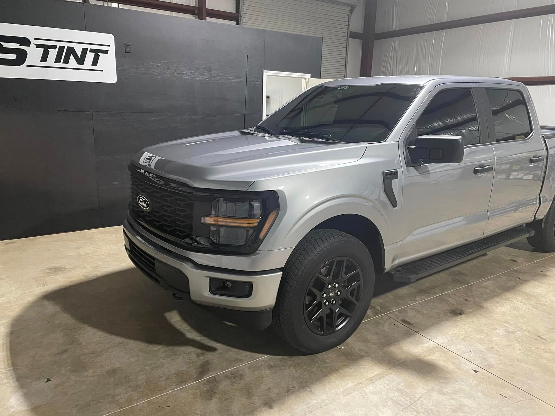 A silver ford f150 truck is parked in a garage.