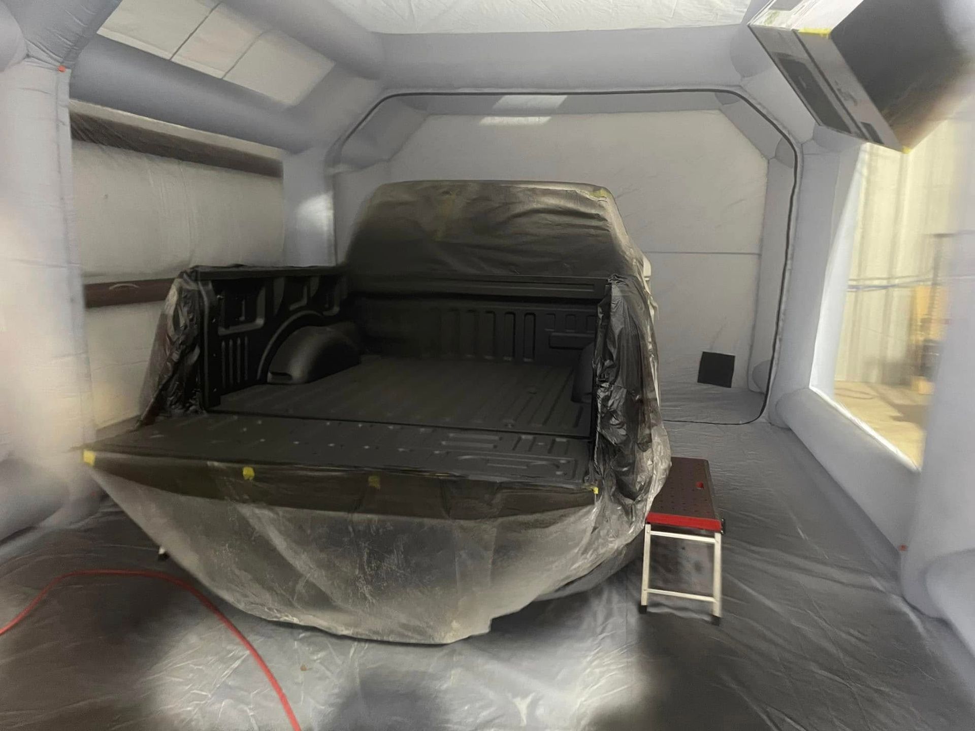 A truck is being painted in a paint booth.