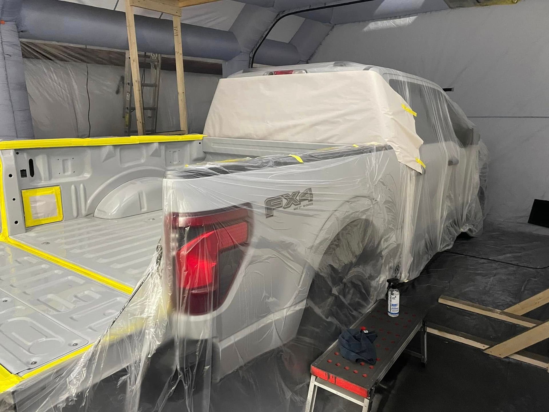 A white truck is being painted in a paint booth.