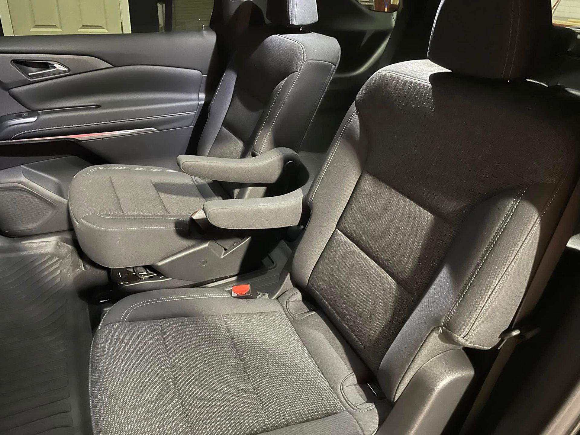 The back seat of a car with a cup holder on the arm rest