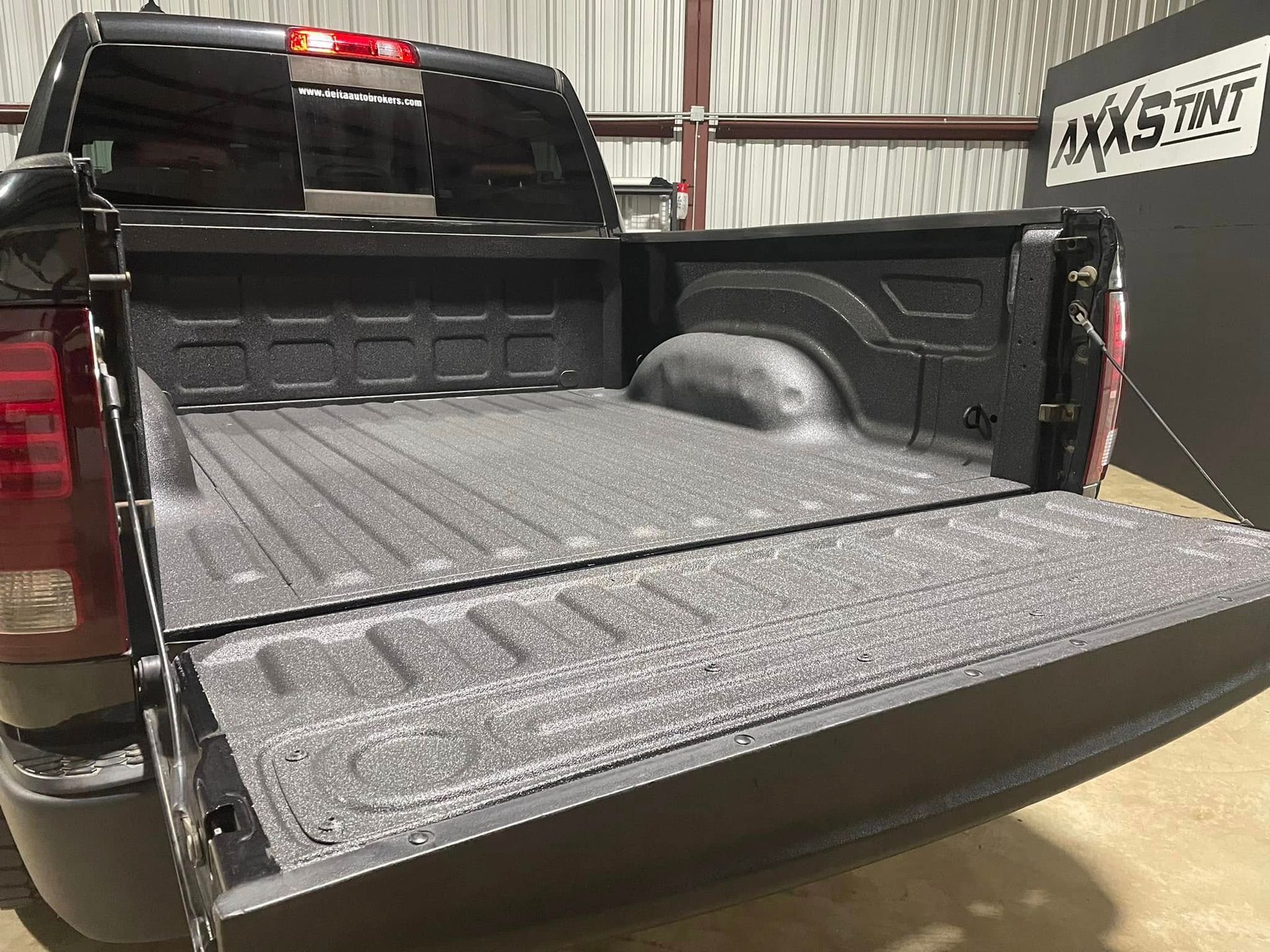 A black truck with the bed open is parked in a warehouse.