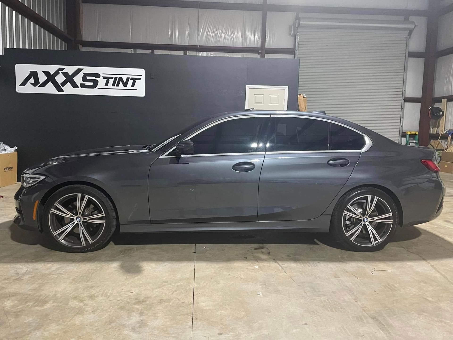 A gray bmw 3 series is parked in a garage.