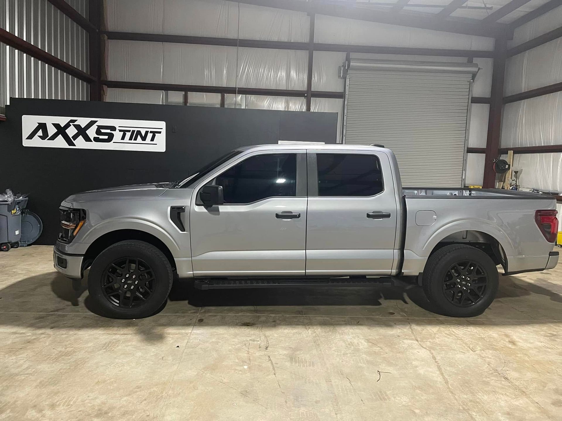 A silver pickup truck is parked in a garage.