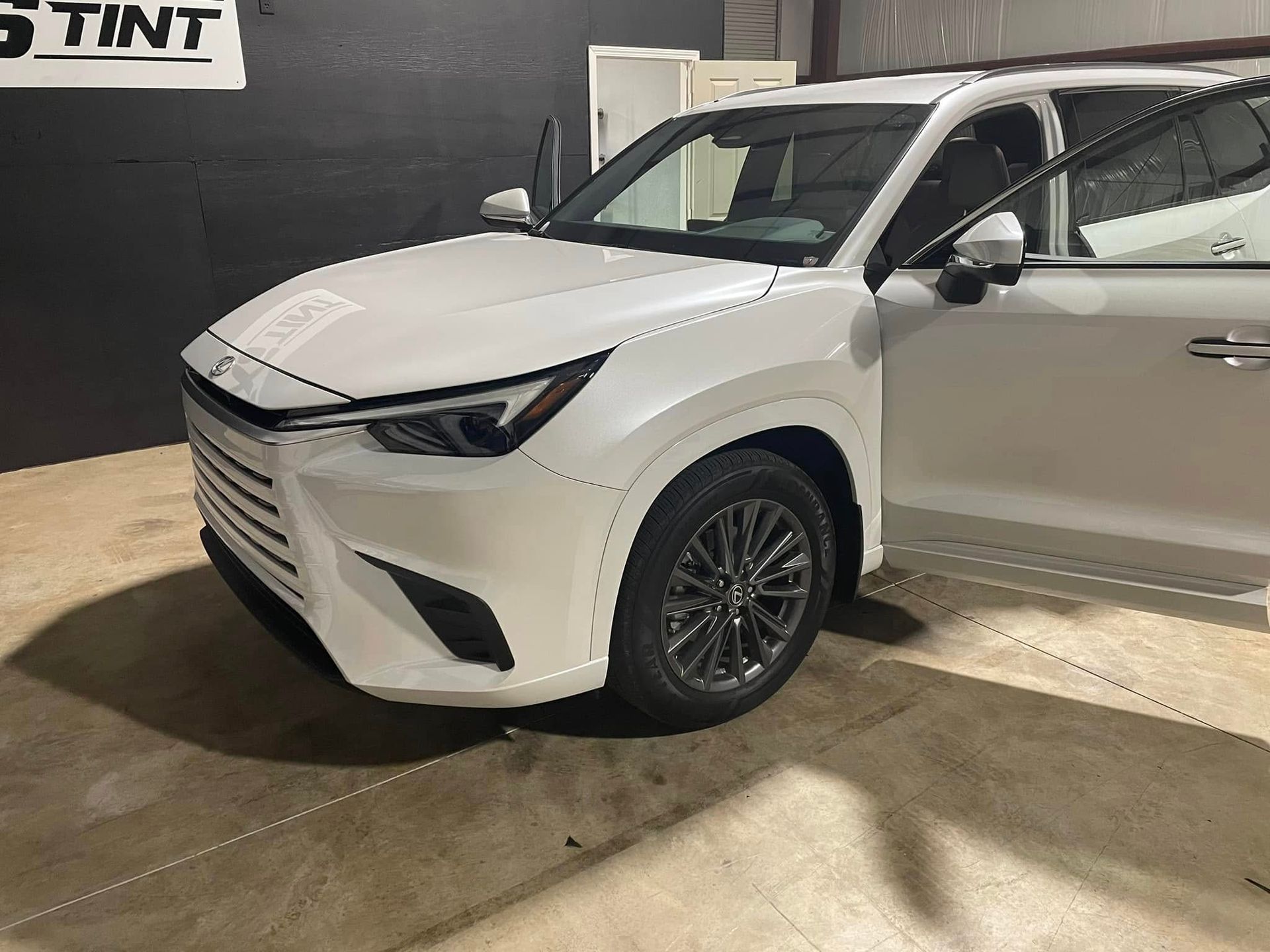 A white car is parked in a garage with its doors open.