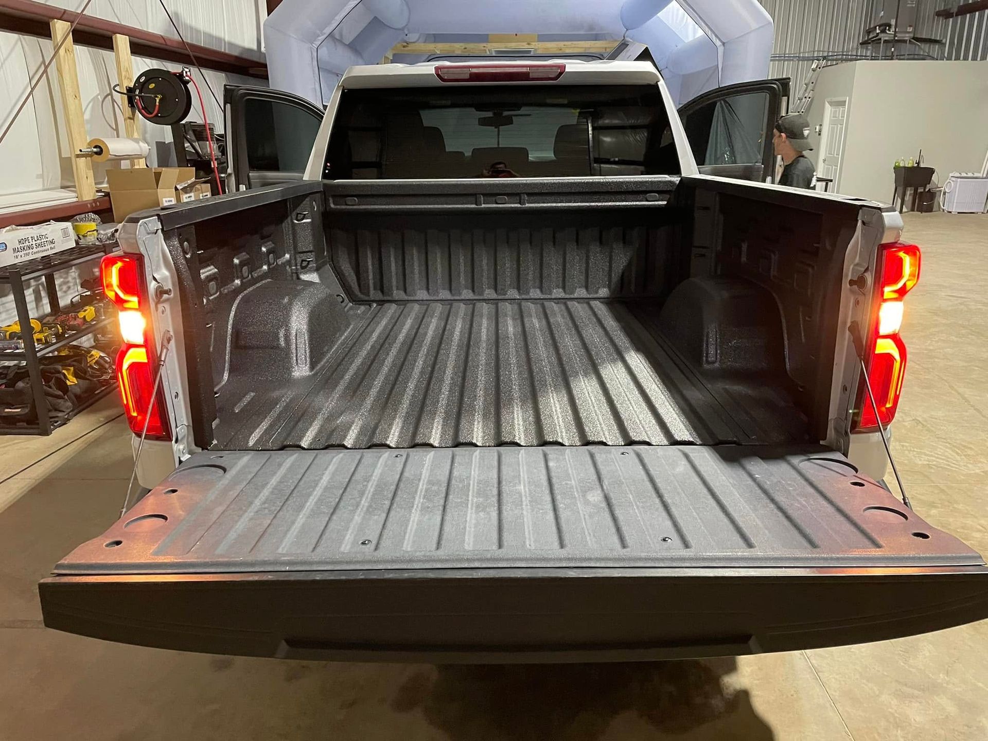 A pickup truck is parked in a garage with the bed open.