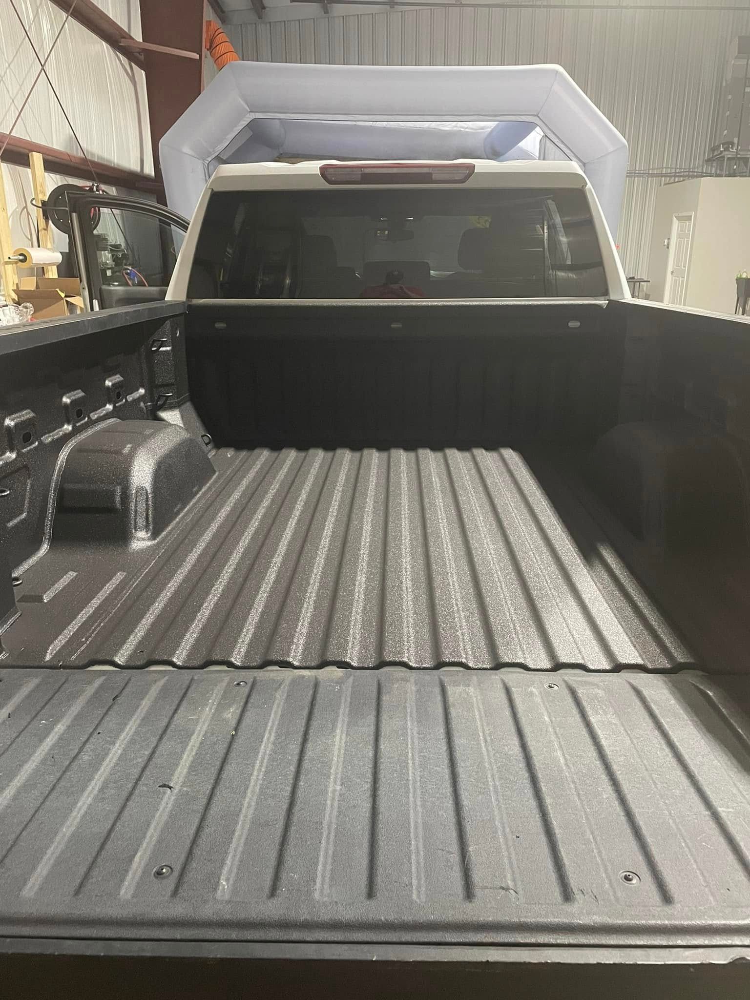 A truck is parked in a garage with the bed open.