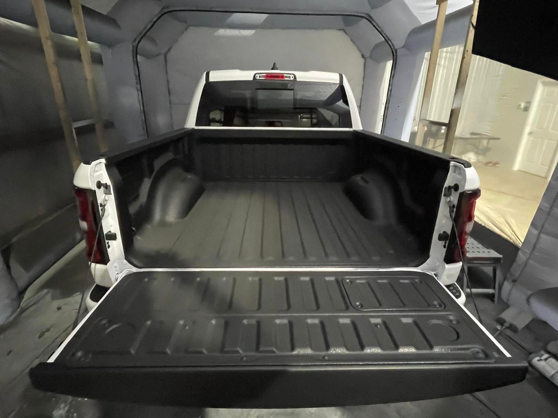 The back of a white truck with the bed open