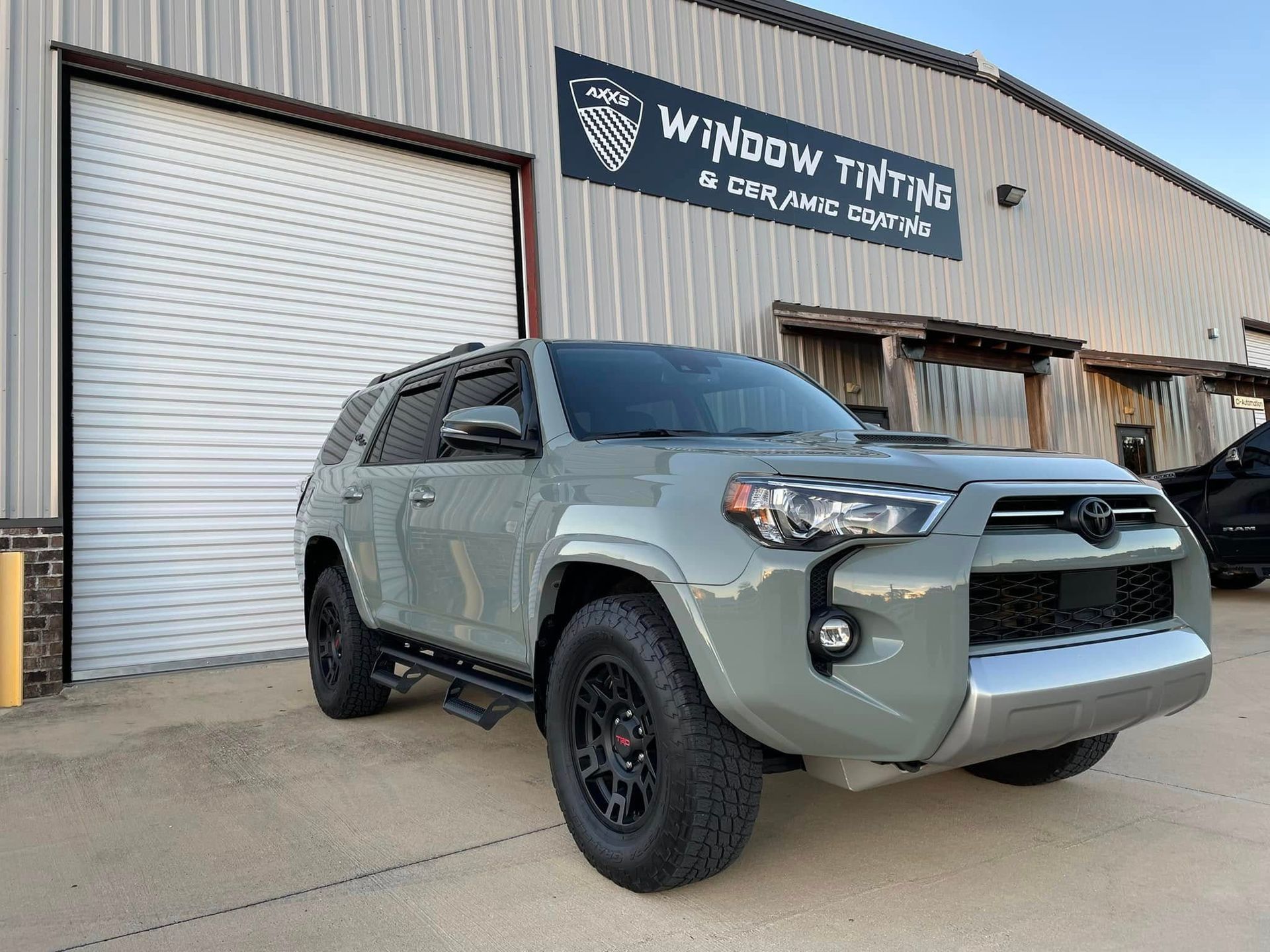 A toyota 4runner is parked in front of a building that says window tinting.