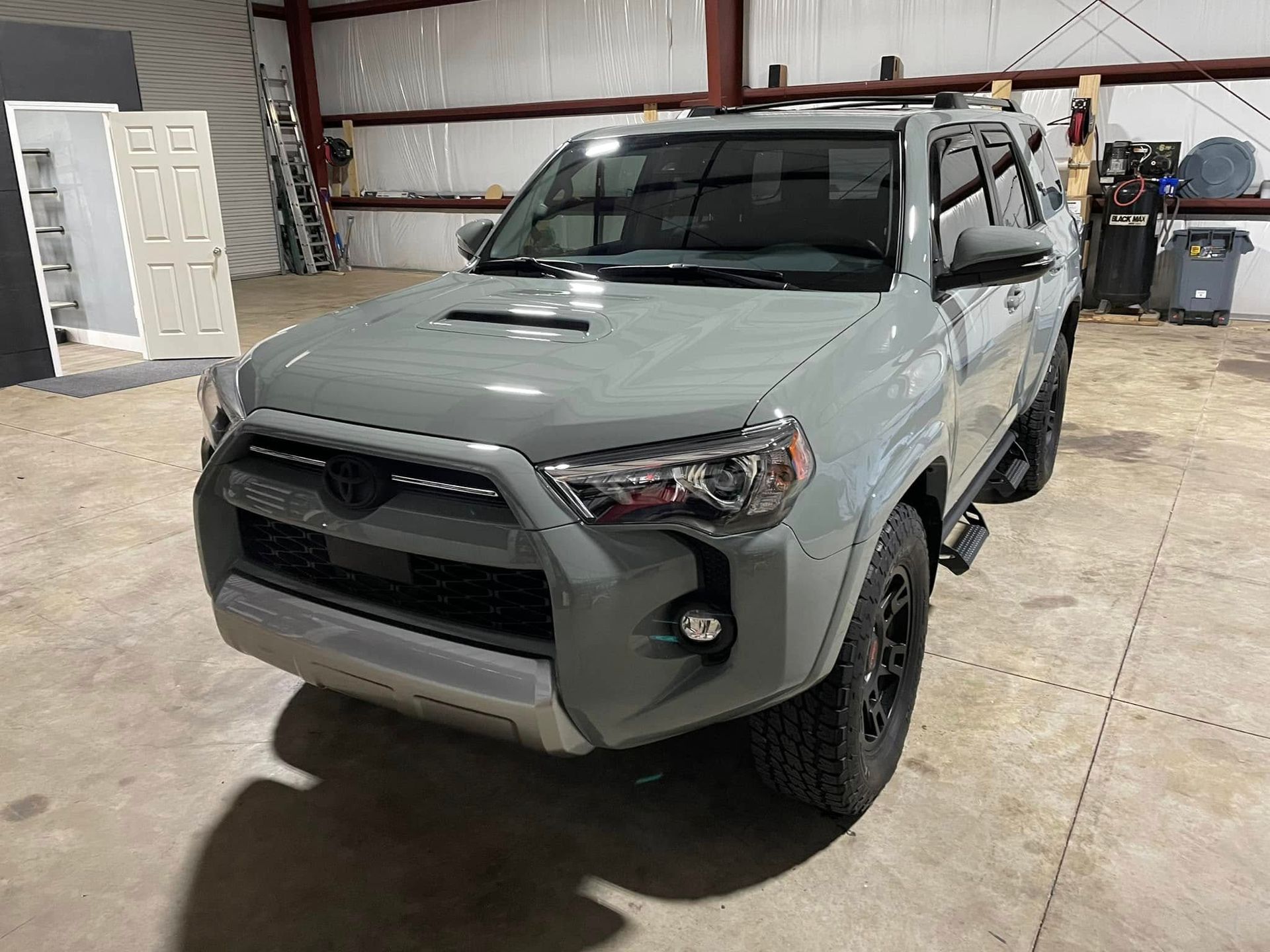 A grey toyota 4runner is parked in a garage.
