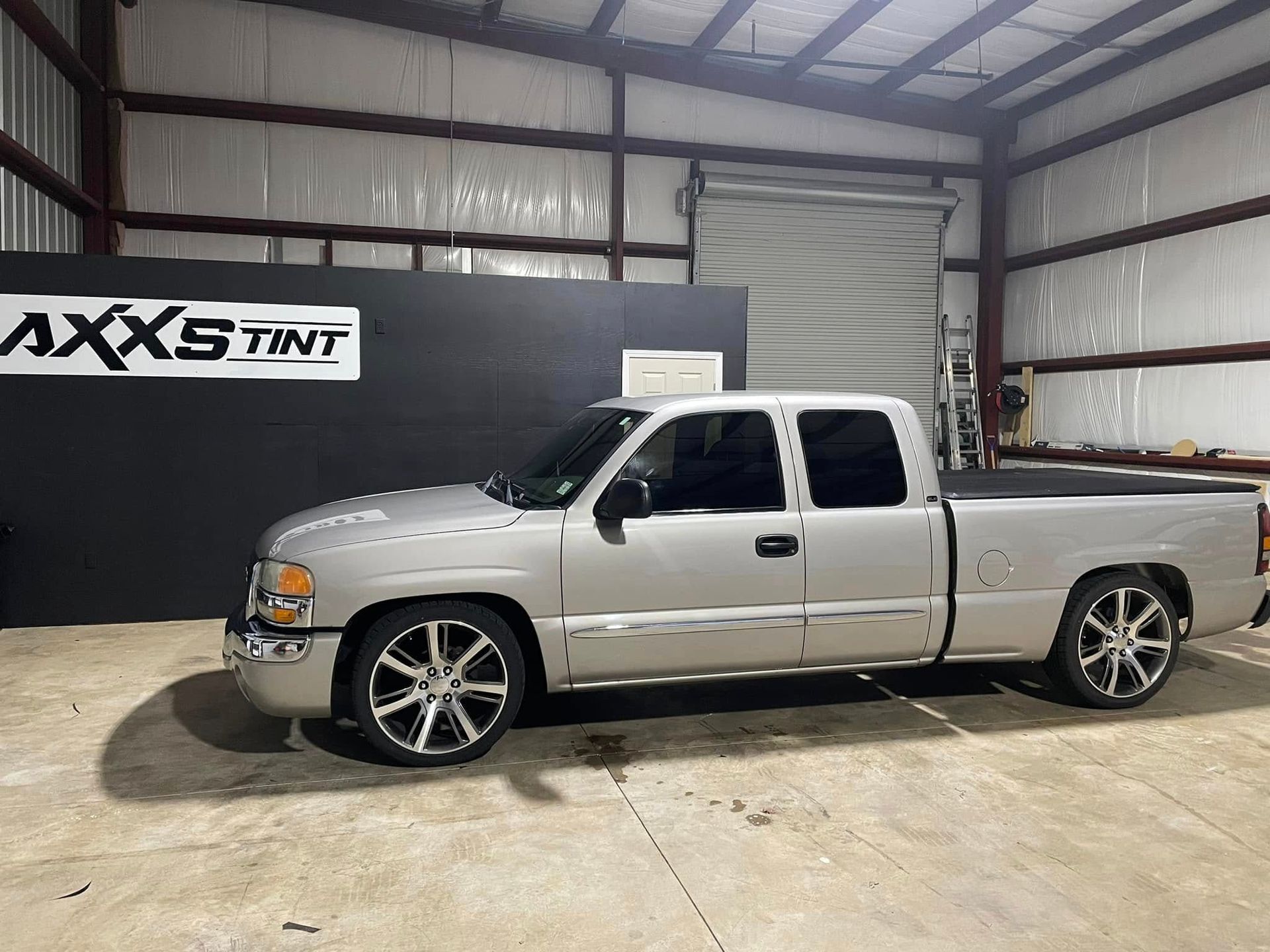 A silver pickup truck is parked in a warehouse.