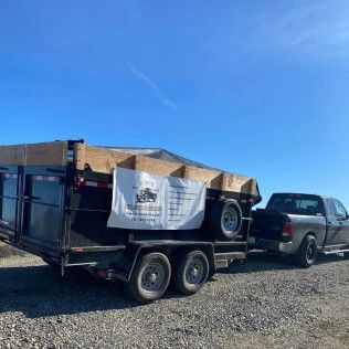 A dump truck is pulling a trailer with boxes on it.