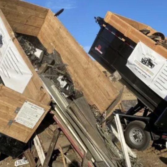 A dumpster is sitting on top of a pile of wooden boxes.