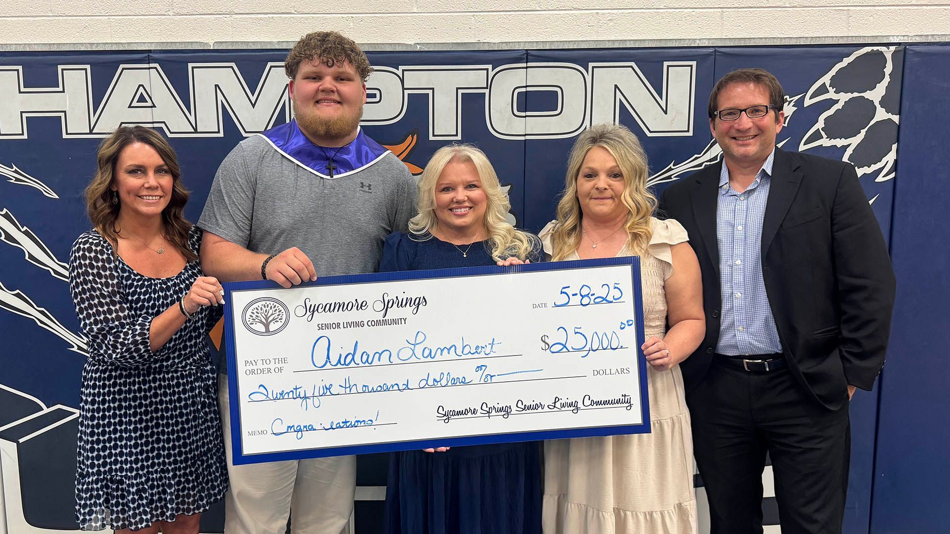 A group of people standing next to each other holding a large check.