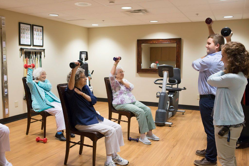 A group of elderly people are doing exercises in a gym.