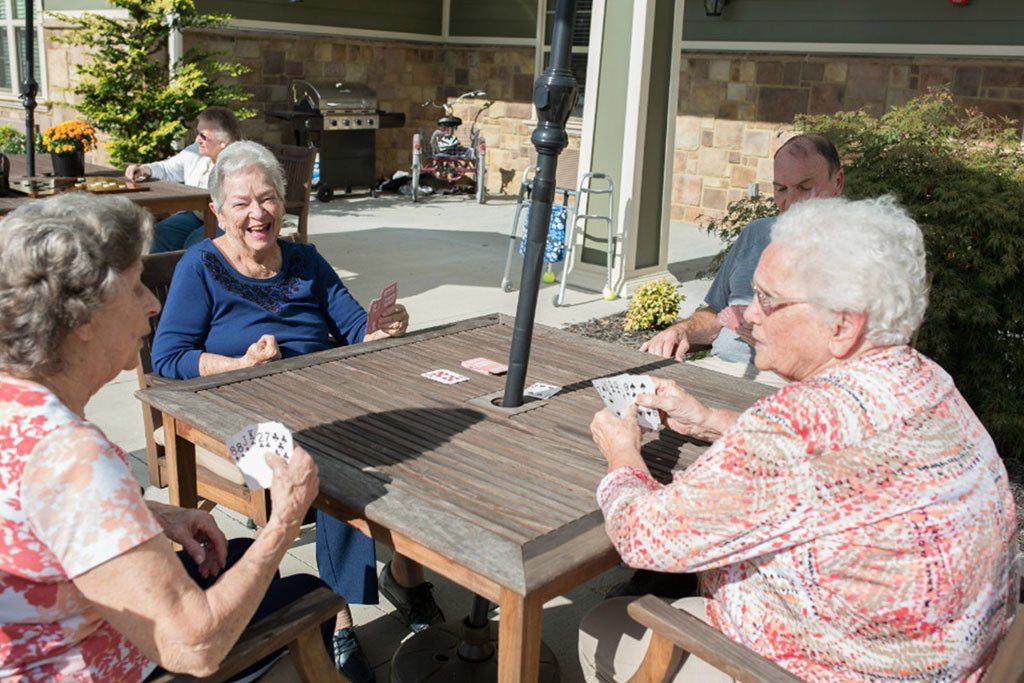A group of elderly people are sitting at a table playing cards.