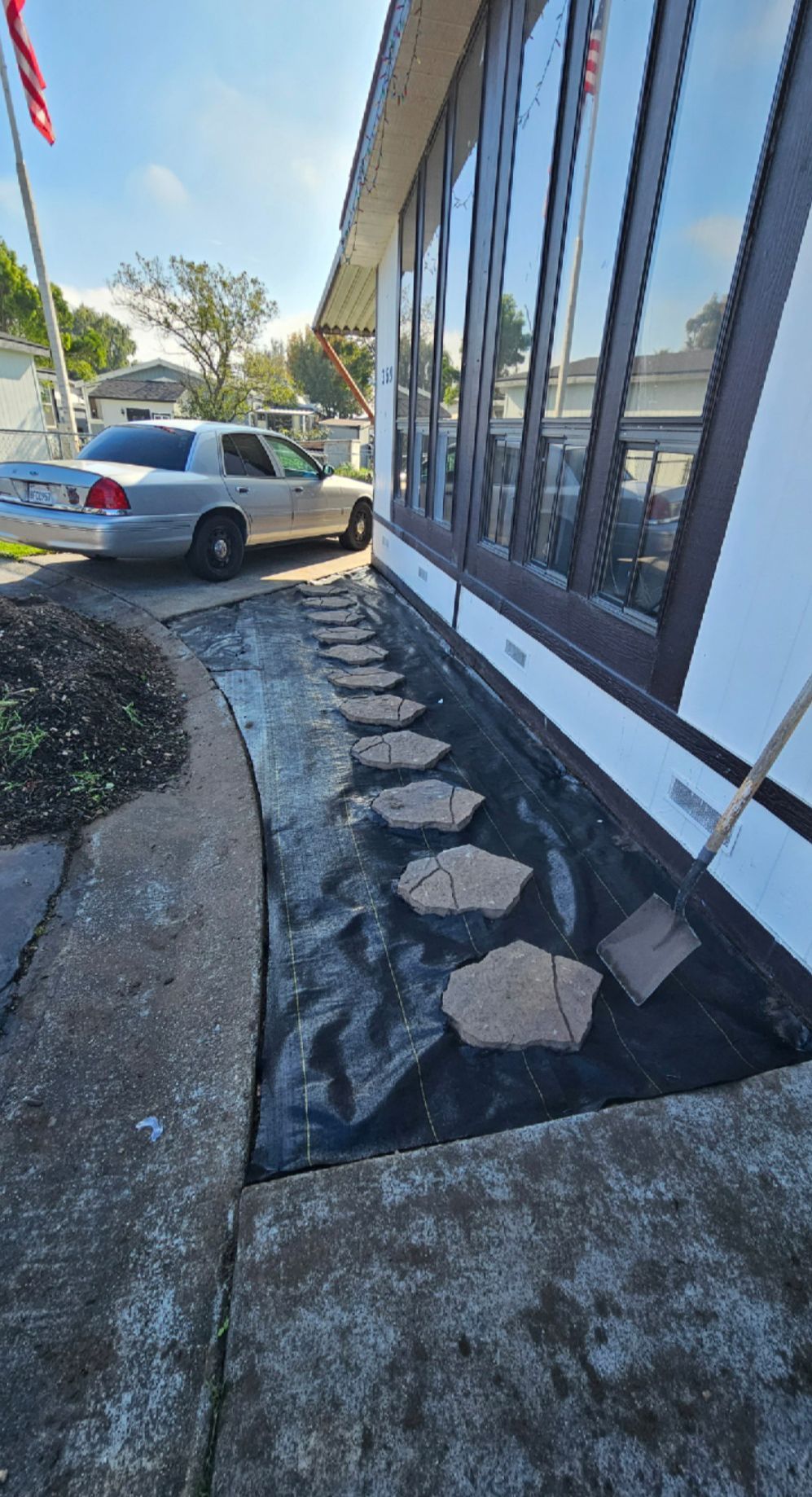 Sidewalk with stepping stones alongside a building with large windows.