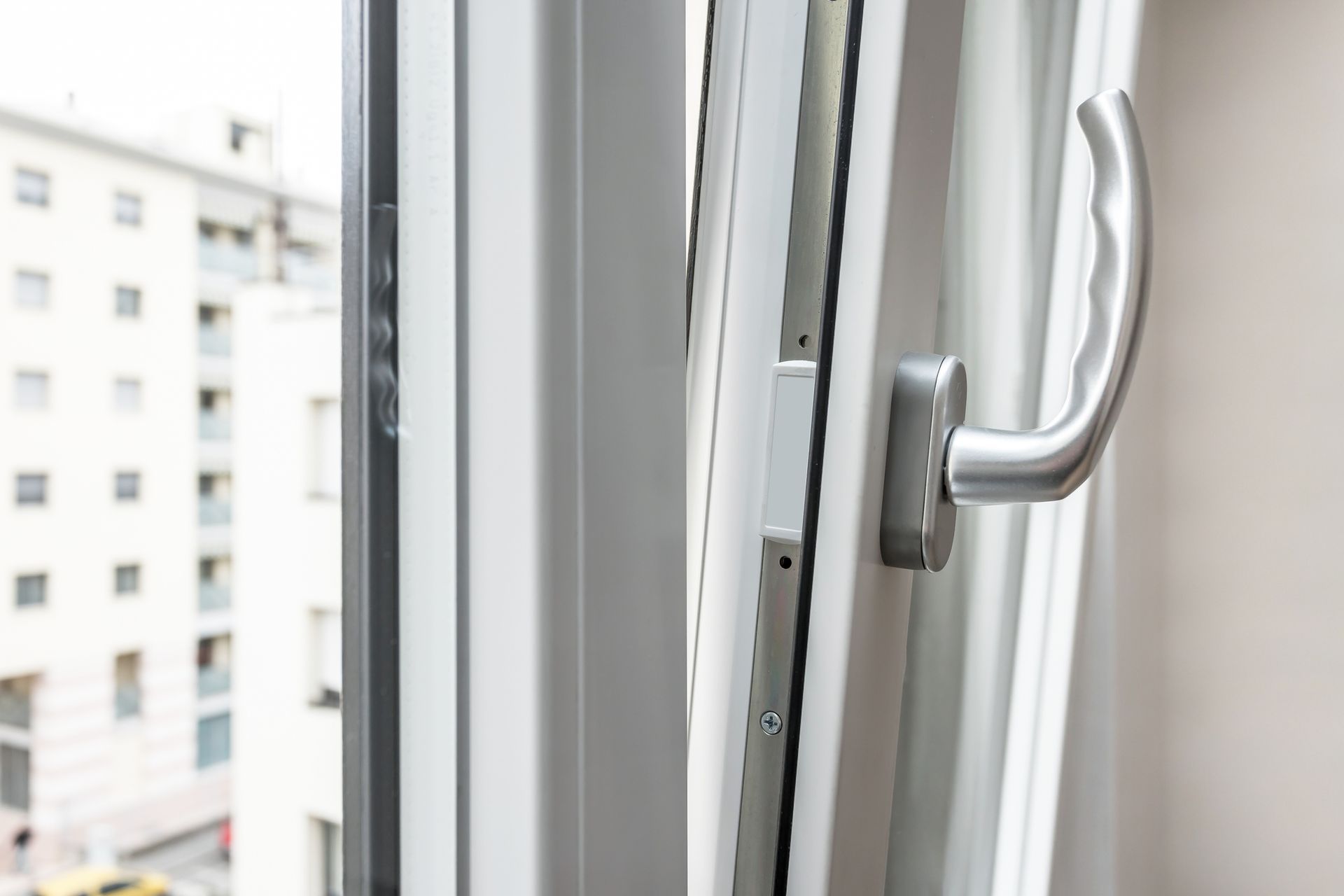 Un primo piano di una finestra aperta con un edificio sullo sfondo.