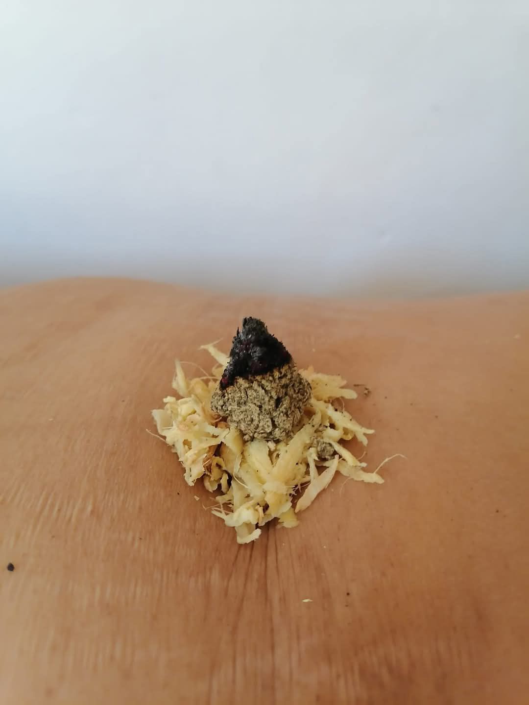 Comida amarilla rallada con pequeños aderezos negros y verdes, sobre una superficie de madera.