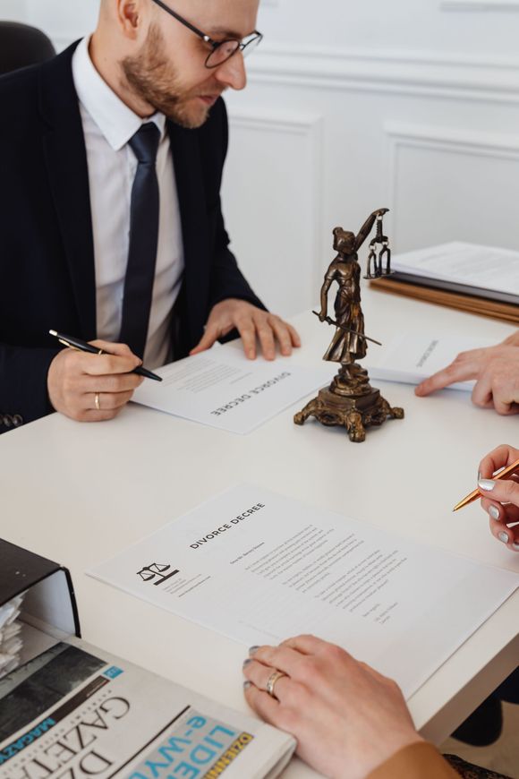 Business meeting with people reviewing documents around a desk with a small justice statue centerpiece