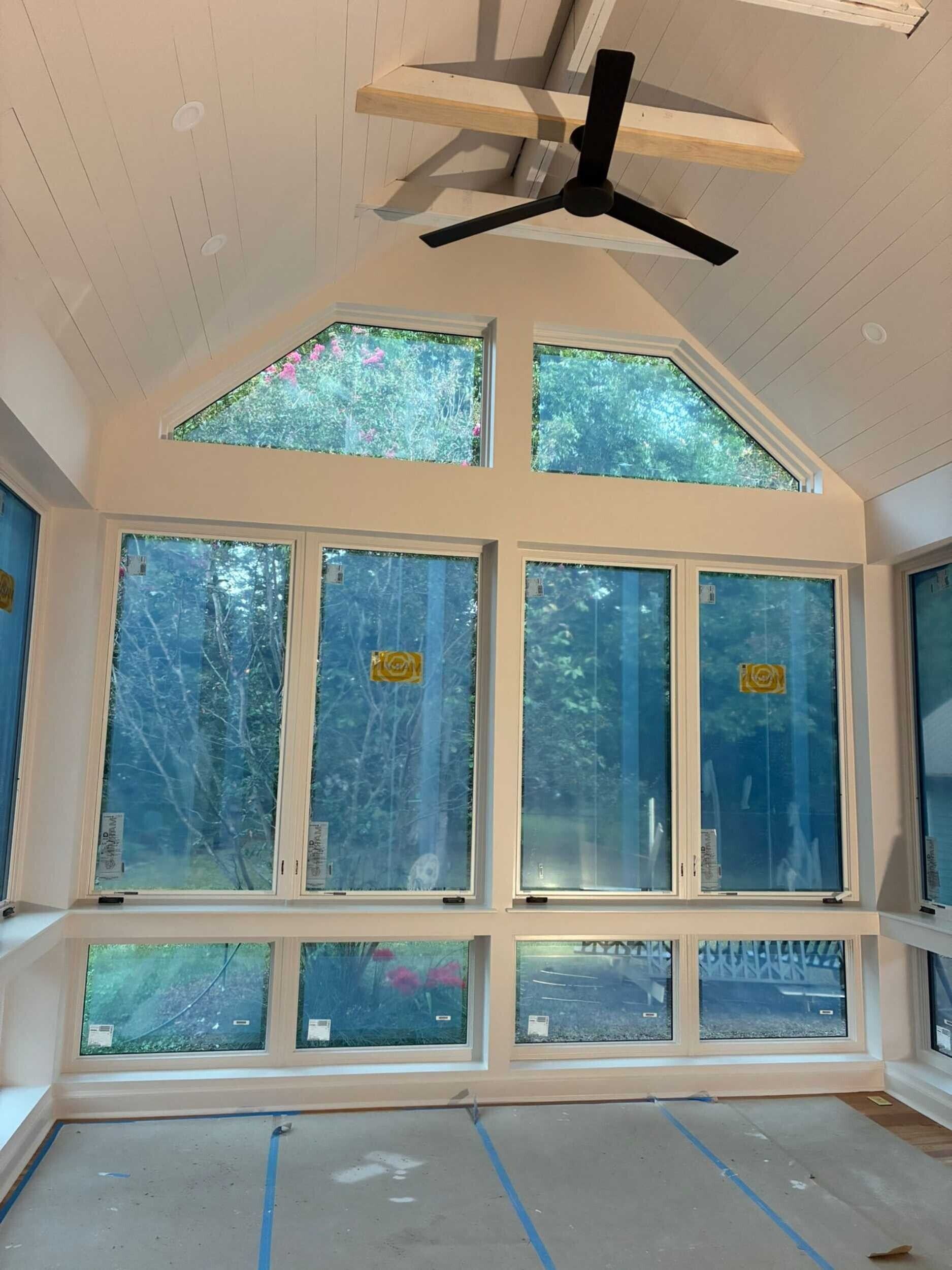 Sunroom interior with large windows, vaulted ceiling, and ceiling fan.