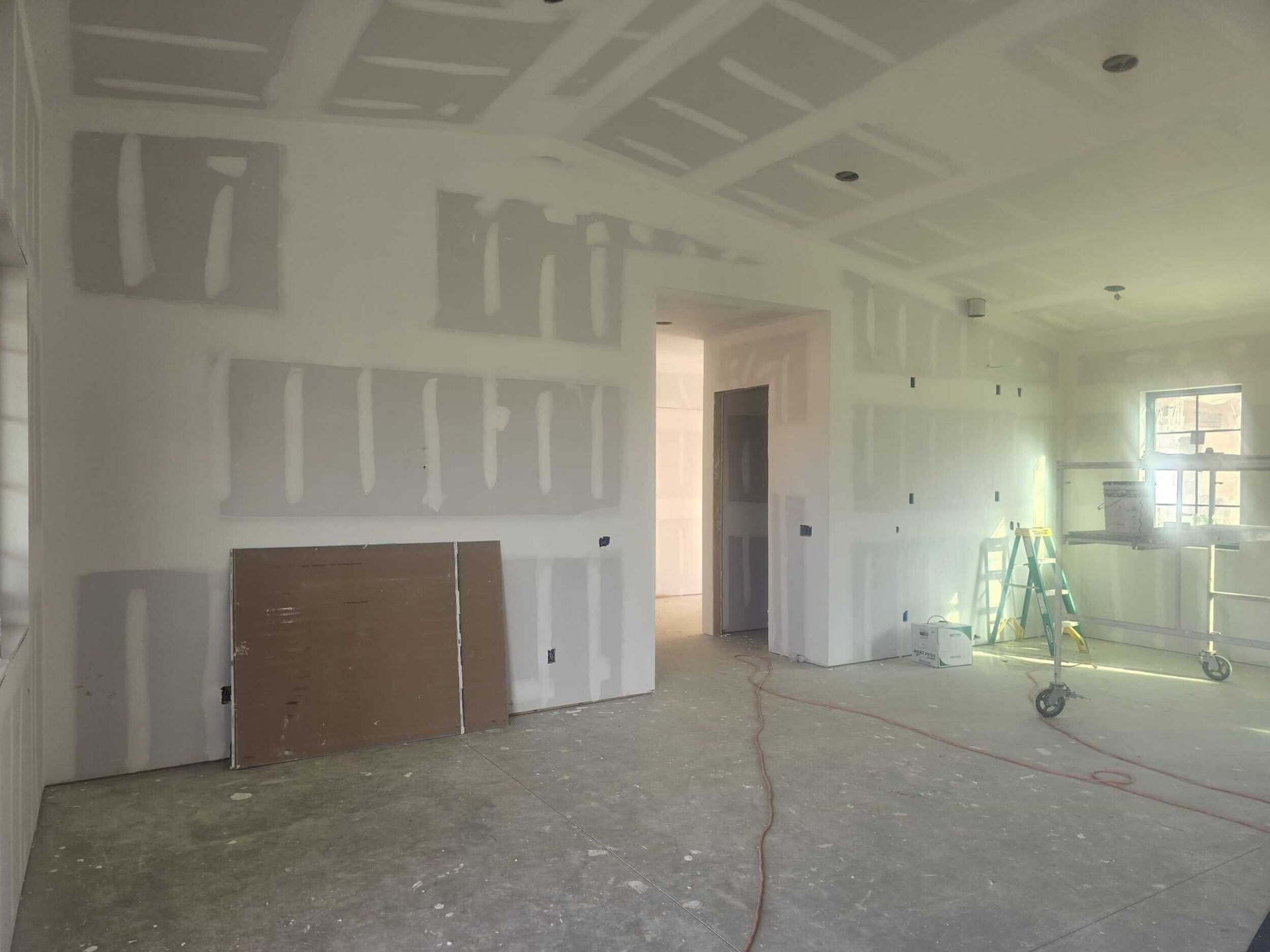 Interior of a room under construction, with drywall installed on walls and ceiling.