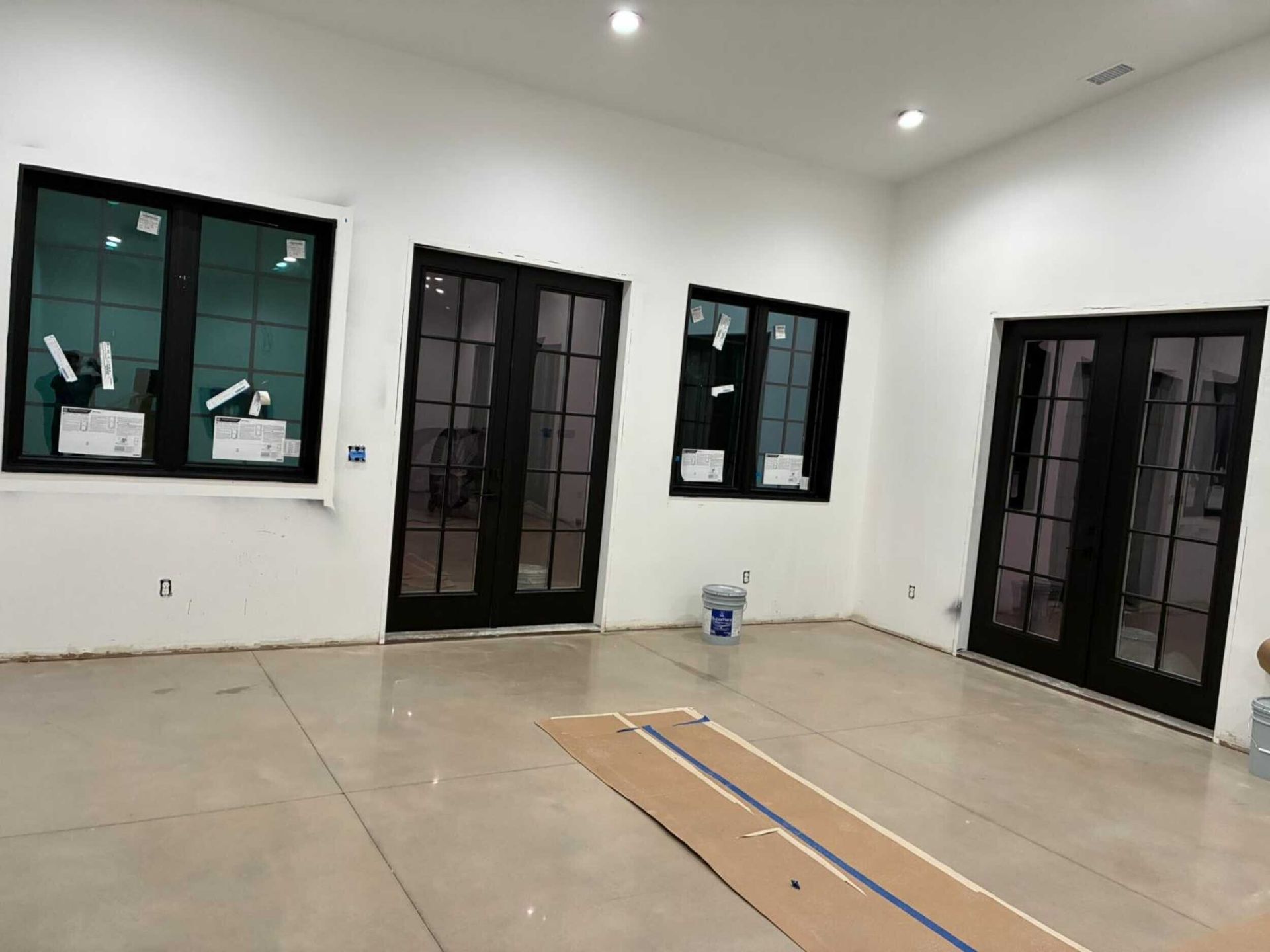 Interior with black framed windows and doors on white walls, concrete floor.