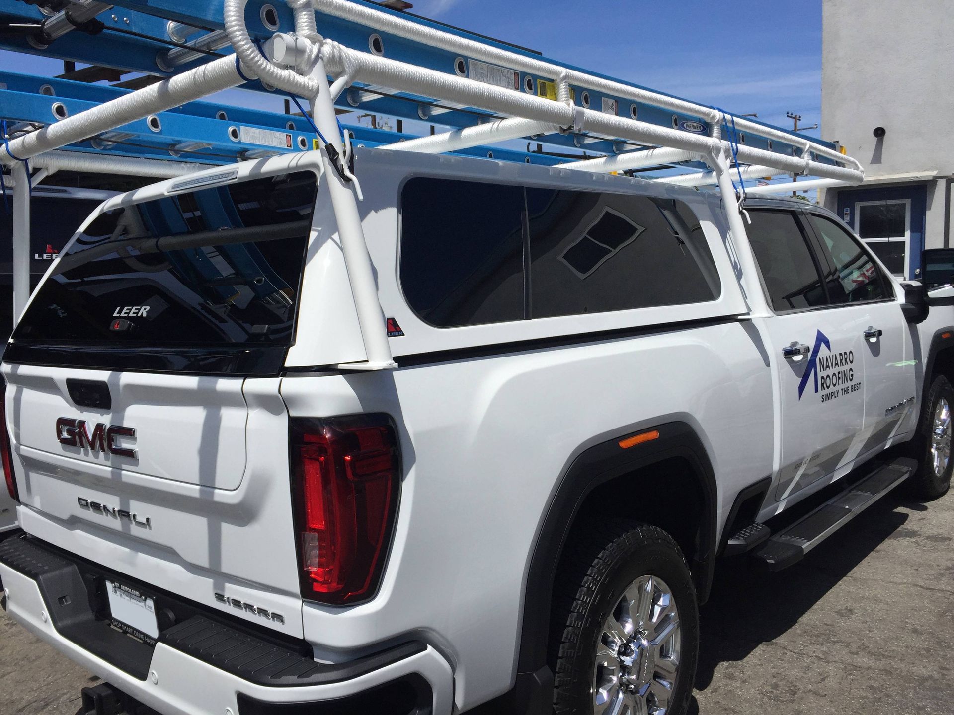 A white gmc truck with a ladder rack on top of it