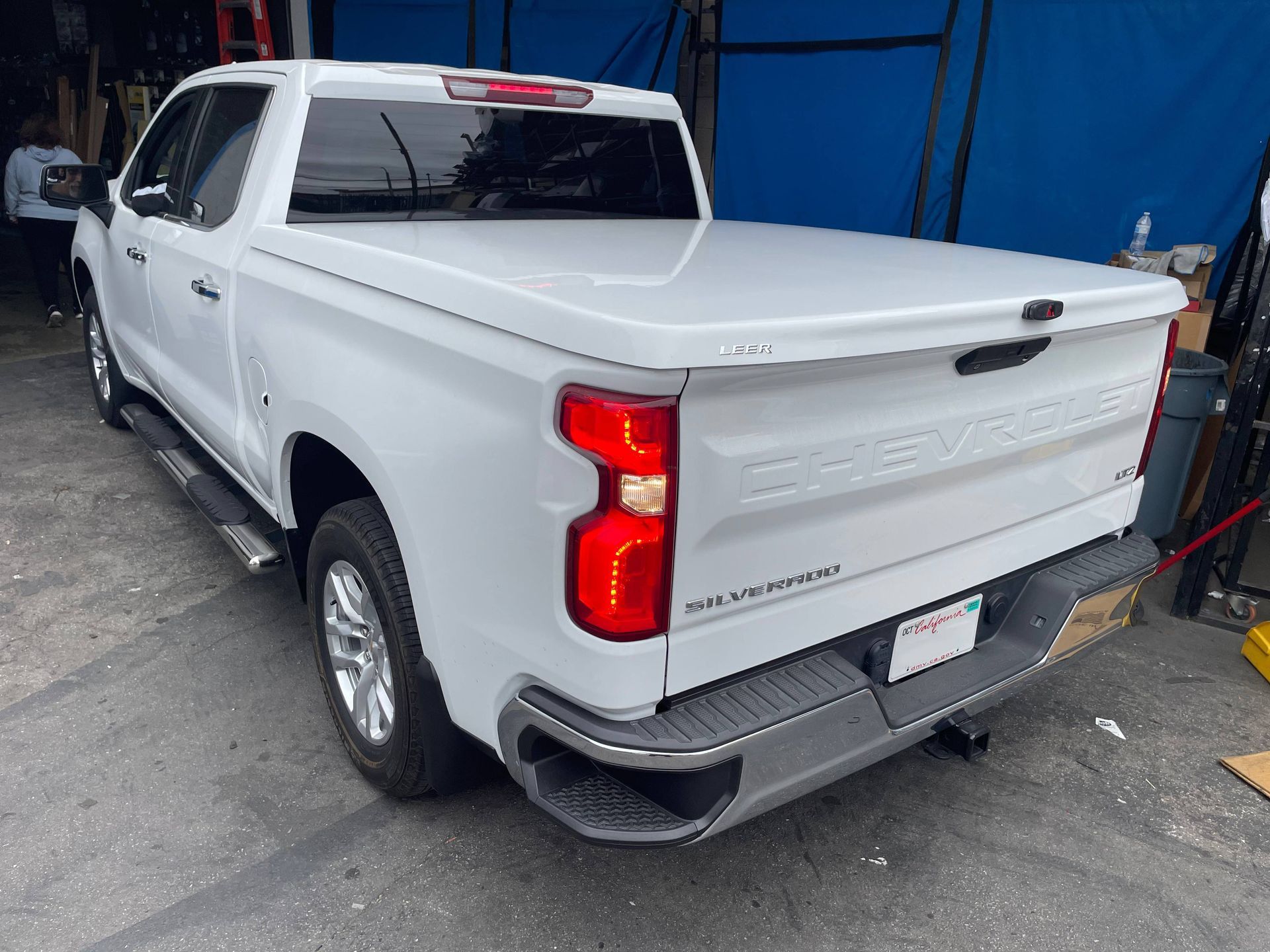 A white truck with a white bed cover is parked in a garage.
