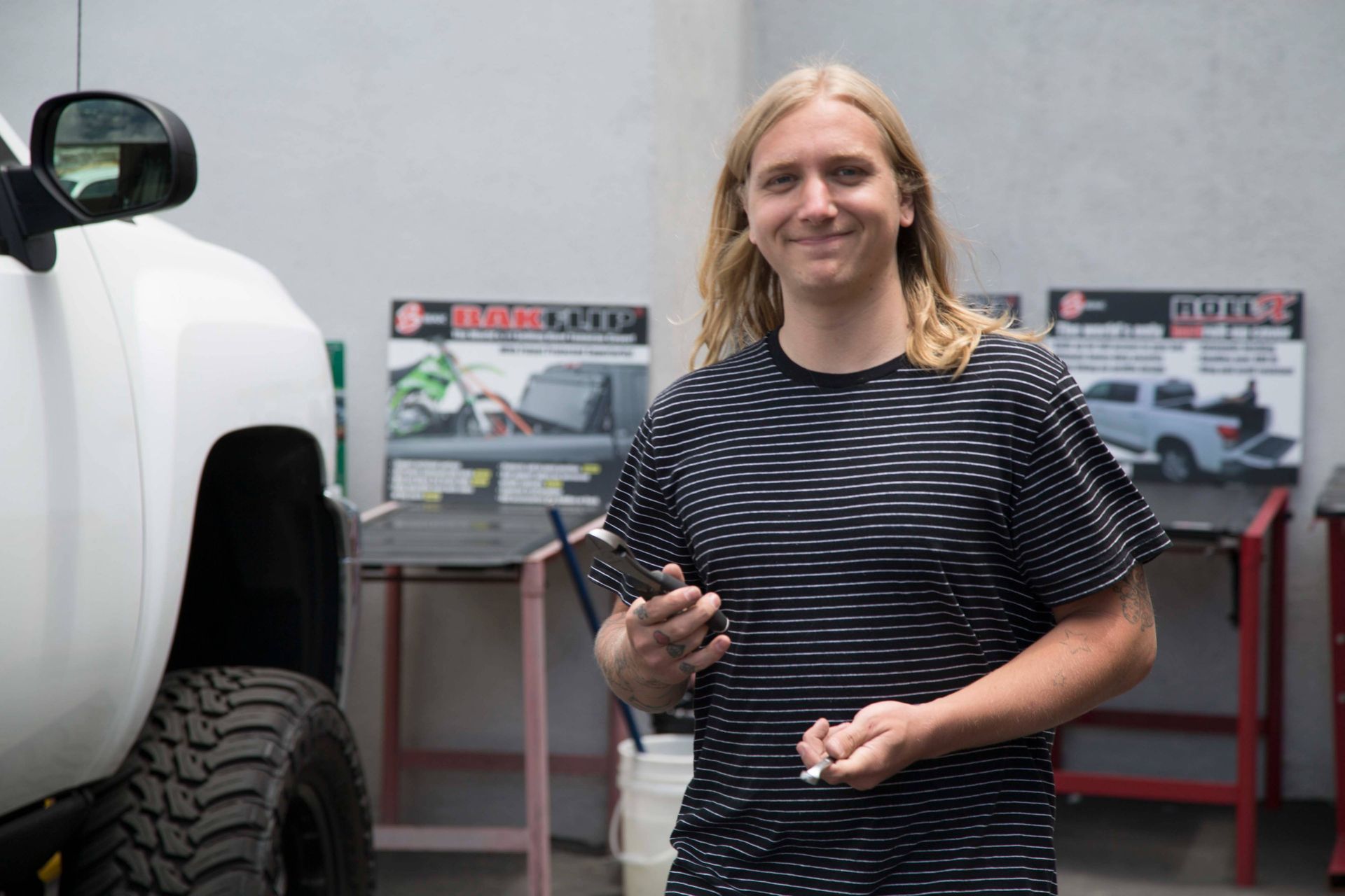 A man is standing in front of a white truck holding a cell phone.