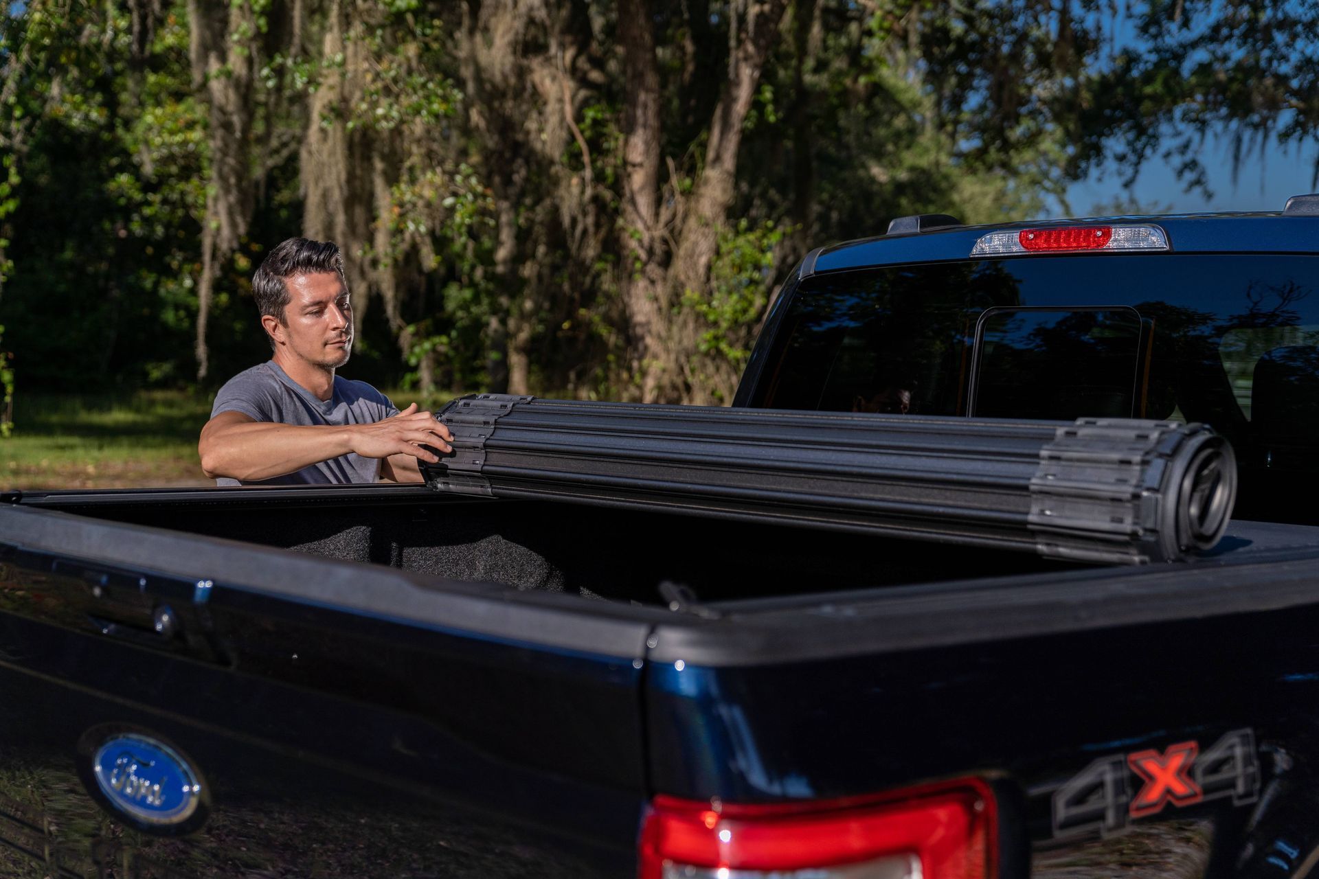 A man is putting a tonneau cover on the back of a truck.