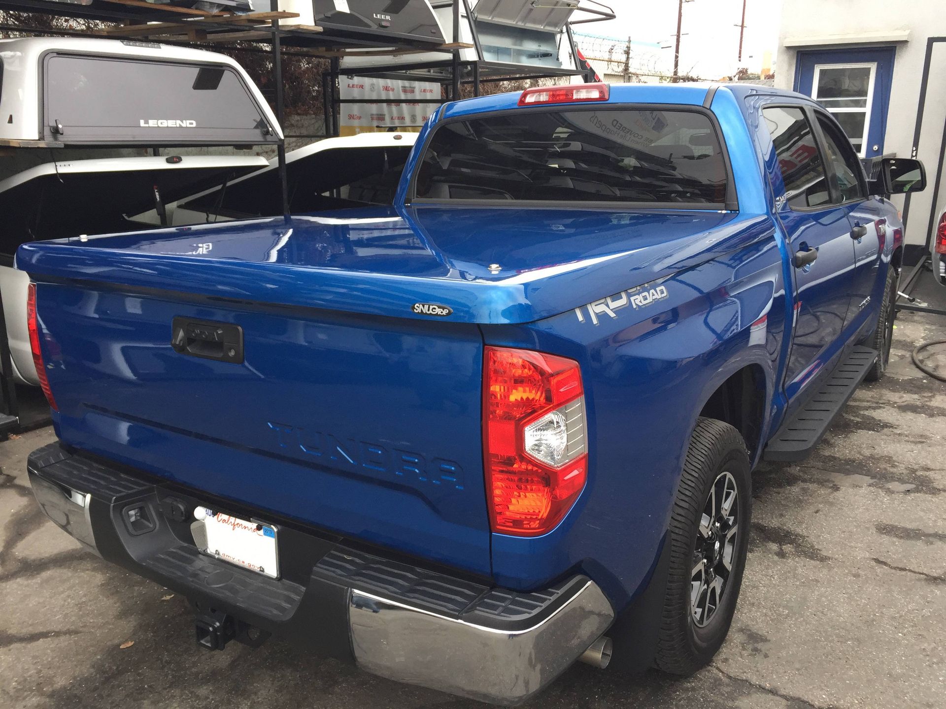 A blue truck with a bed cover is parked in a parking lot.