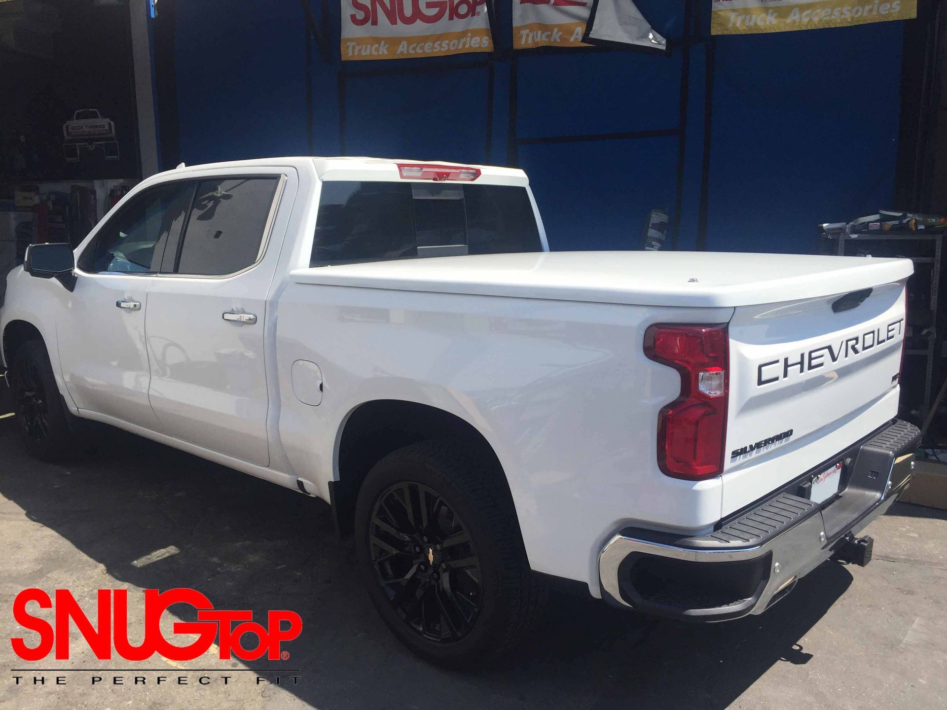 A white chevrolet truck is parked in front of a blue building.