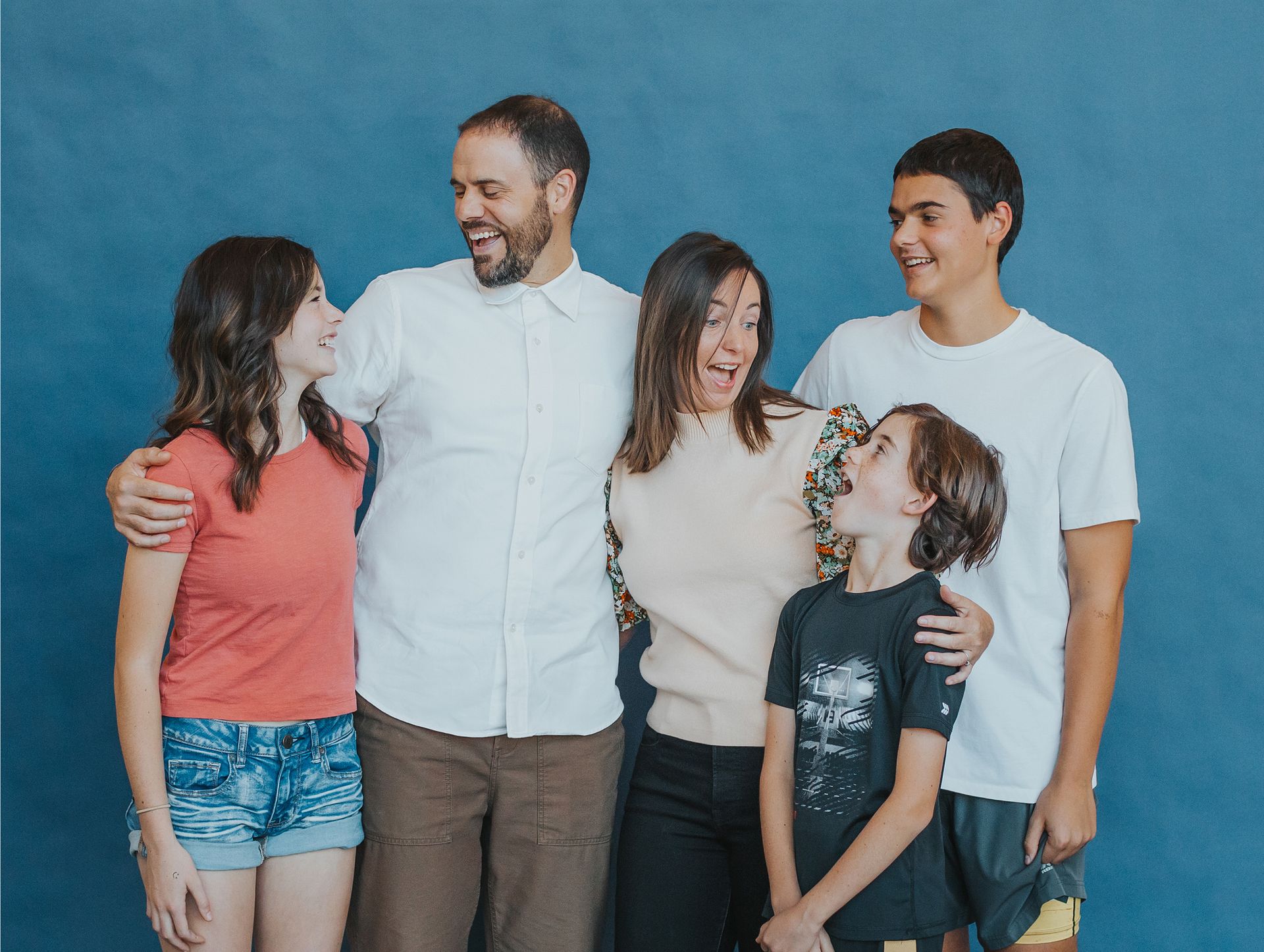 A family is posing for a picture together in front of a blue wall.