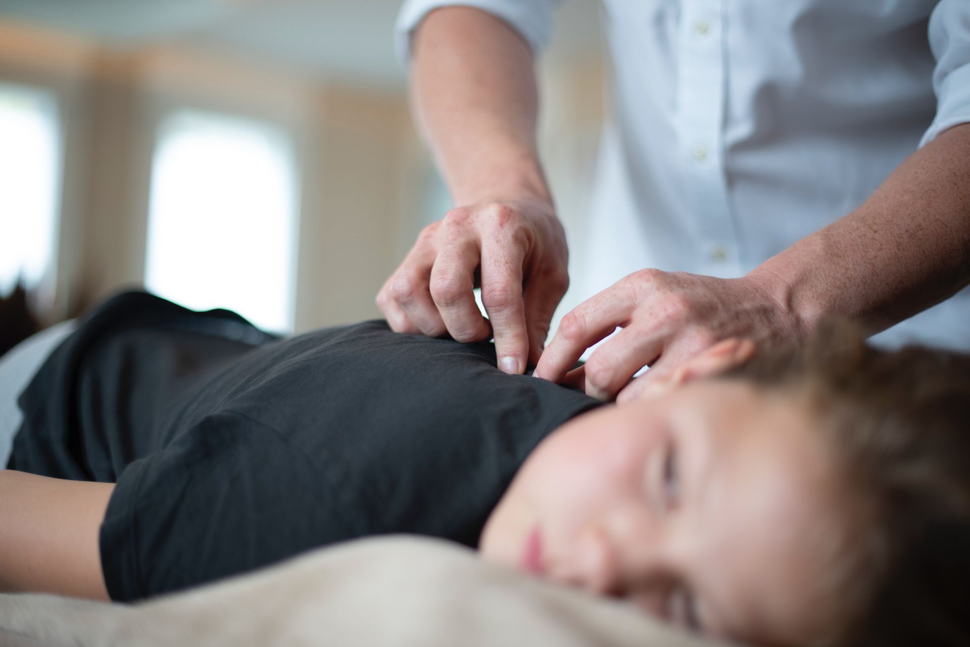 a young boy is laying on a bed getting acupuncture from a doctor .