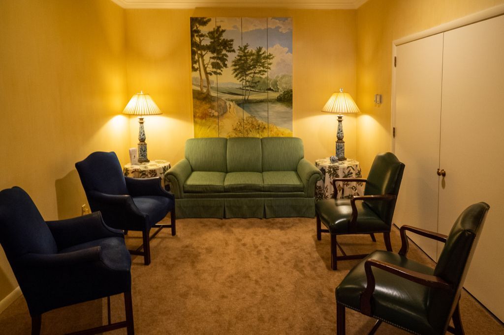 a living room with a couch and chairs and a painting on the wall .