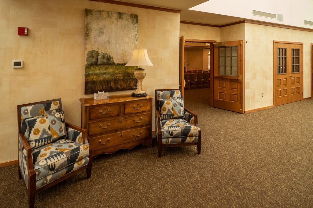 there are two chairs and a dresser in the hallway .