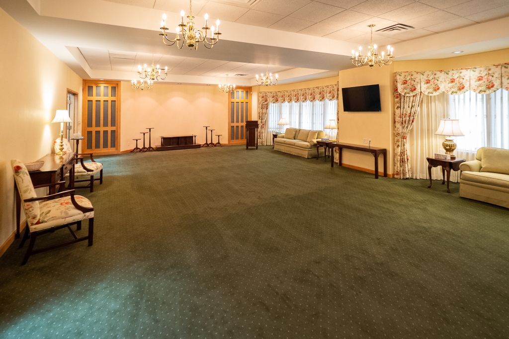 a large room with green carpet and a flat screen tv on the wall .