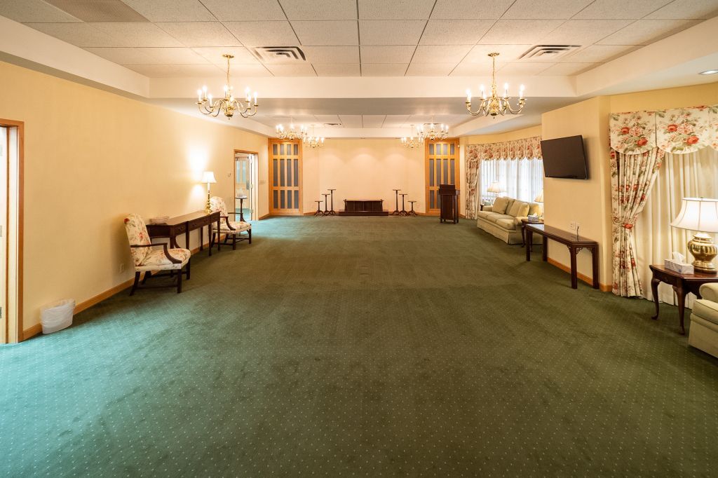 an empty room with green carpet and a television on the wall .