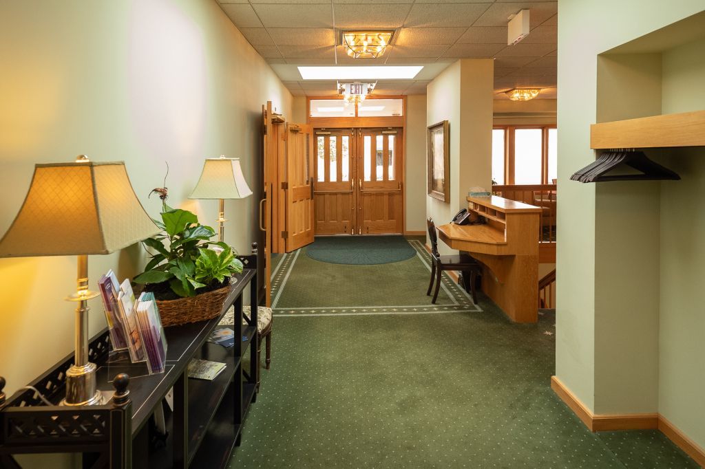 a hallway with green carpet and two lamps