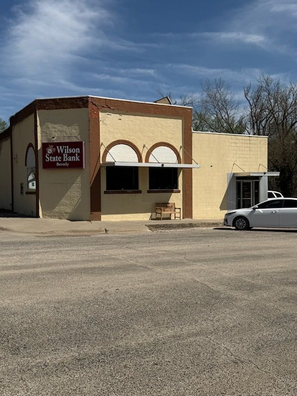 A white car is parked in front of a building that says walking sheep farm