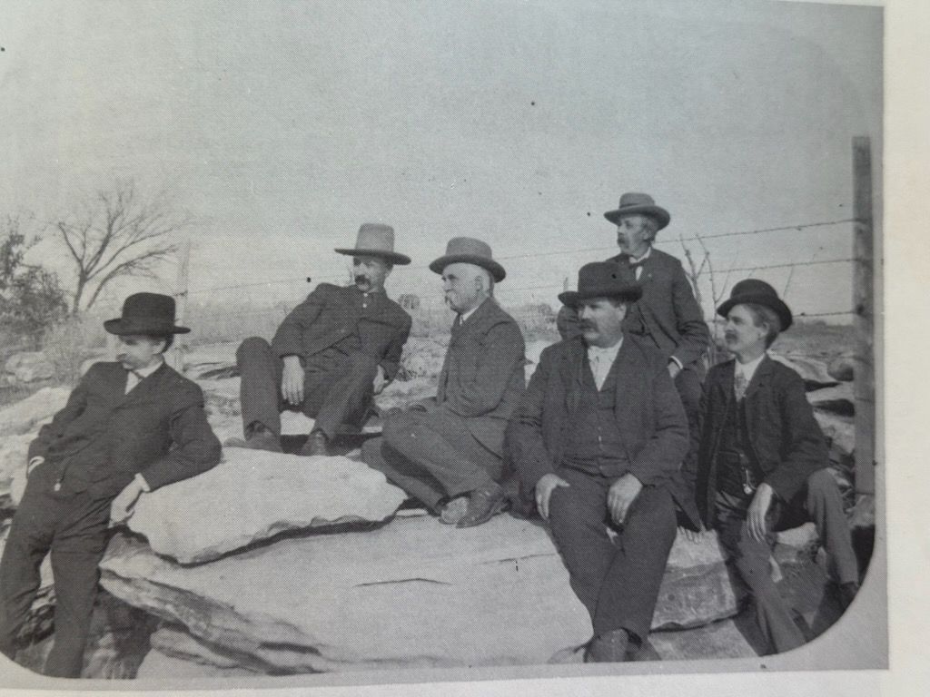 A group of men are sitting on a rock in a black and white photo