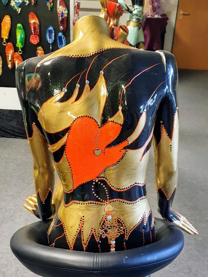 Eine schwarz-goldene Statue mit einem roten Herz auf dem Rücken