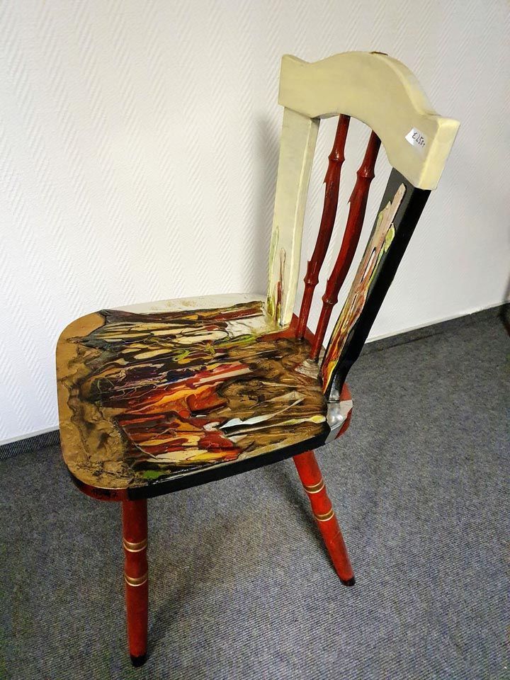 Ein Holzstuhl mit einem Gemälde auf der Sitzfläche