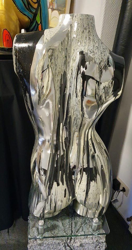 Auf einem Tisch sitzt eine Statue eines Frauentorsos.
