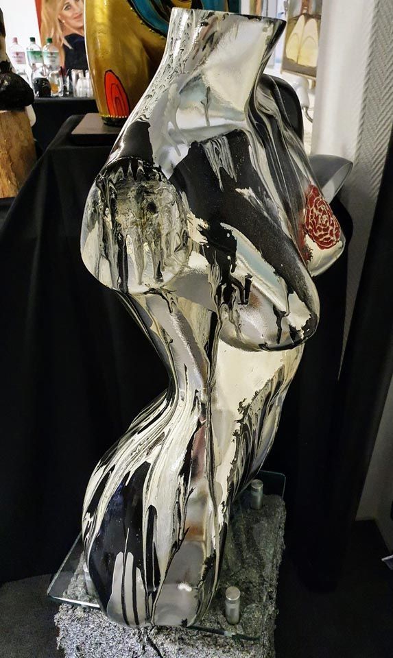 Auf einem Tisch steht eine schwarz-weiße Skulptur eines Frauentorsos.