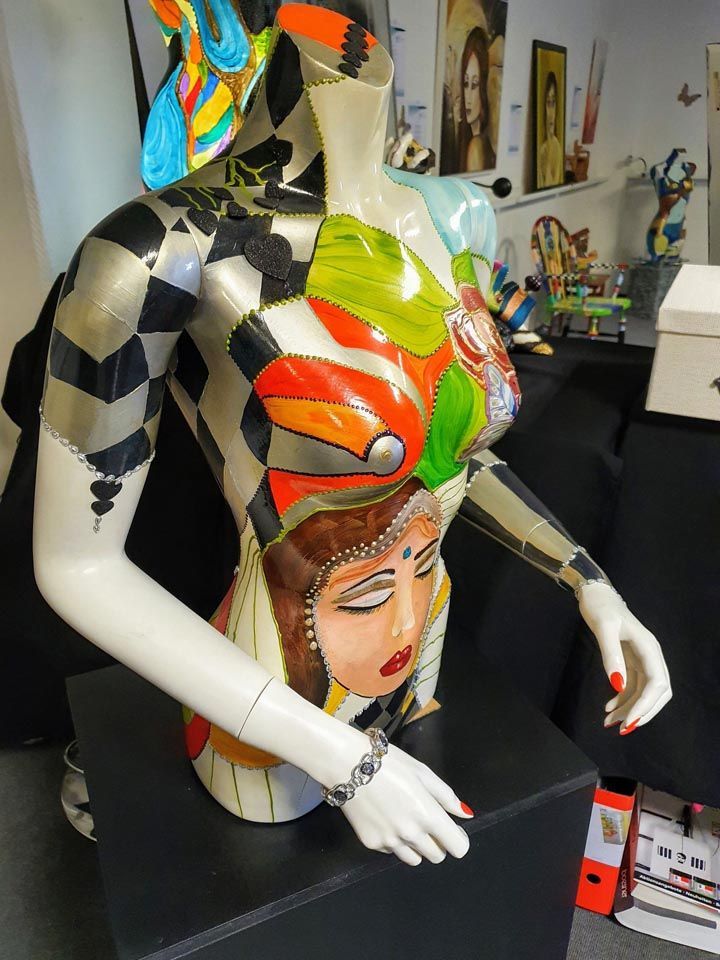 Eine bunte Statue einer Frau sitzt auf einer schwarzen Kiste
