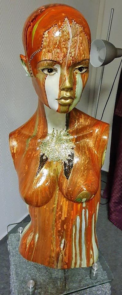 Auf einem Glastisch sitzt eine Statue eines Frauentorsos.