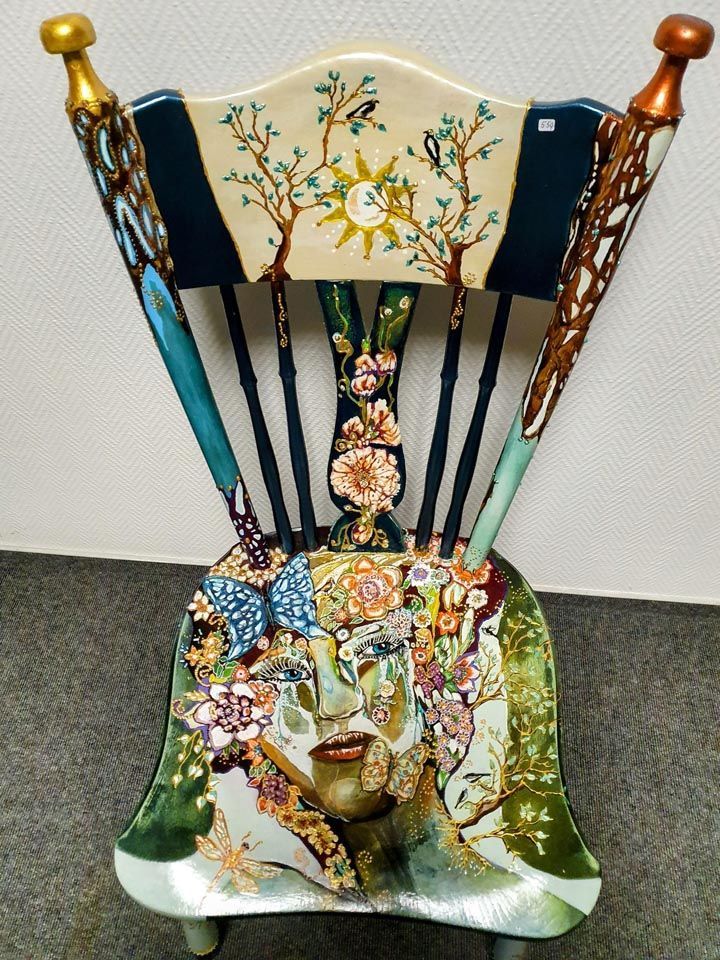 Ein Stuhl mit einem Gemälde von Bäumen und Blumen darauf